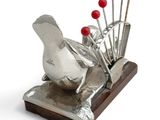 a silver sculpture of a bird with red berries on it