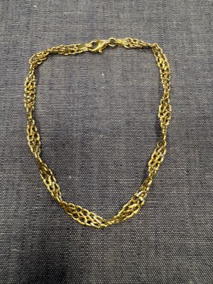 un collier à chaîne en or posé sur un tissu gris