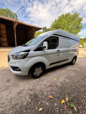 a white van parked in front of a barn with a blue sky