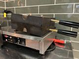 une image représentant un grill à hot-dogs sur lequel sont posées des pinces