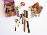 une boîte rose sur laquelle sont posés une montre, une cuillère et quelques pièces de monnaie