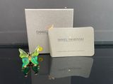 une image représentant une figurine de papillon verte et jaune posée à côté d'une boîte