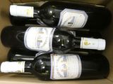 six bottles of wine in a cardboard box sitting on top of a table