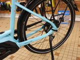 a blue bicycle parked in a store with a black handlebar