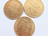 trois pièces d'or superposées sur une surface blanche