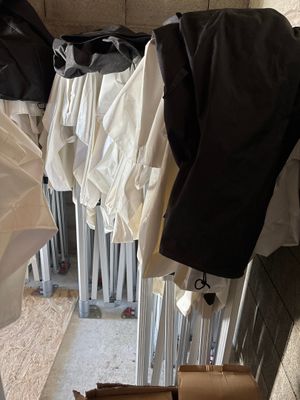 beaucoup de vêtements suspendus au mur, à côté d'une poubelle