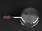 an overhead view of a silver plate with a wooden handle on a black surface