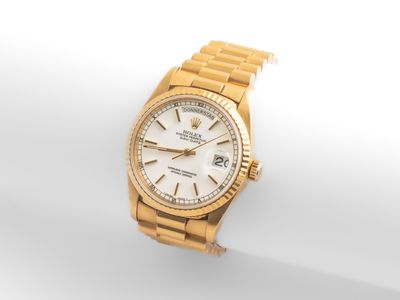 une montre Rolex en or avec un cadran blanc et un bracelet blanc