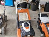 Plusieurs tondeuses à gazon sont alignées dans un garage