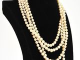 a white pearl necklace on a black mannequin