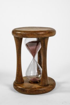 une image représentant un sablier en bois posé sur une table