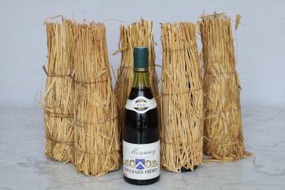 a bottle of wine sitting next to a bunch of straw