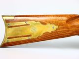 a close up of a rifle with a wooden body and brass accents