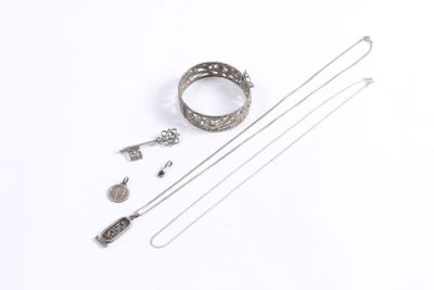 an assortment of silver jewelry on a white surface with a white background