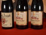 three bottles of wine sitting on a table next to a clock