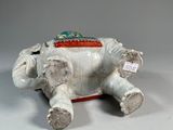 a white elephant sitting on a white surface with a tag on it ' s back