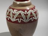 a brown vase with a red and white design on it