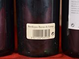 three bottles of wine are lined up on a red cloth