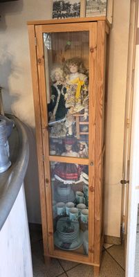 a tall wooden cabinet with a glass door in a kitchen