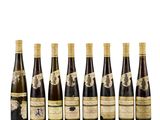 six bottles of wine lined up in a row on a white surface