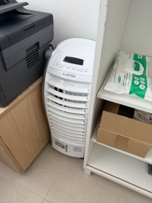 un petit climatiseur posé à côté d'une petite armoire