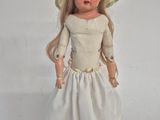a doll that is wearing a white dress and a hat