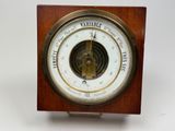une horloge en bois et en laiton, avec un baromètre au centre