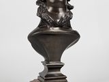 a bronze bust of a man with a hat on top of a wooden base