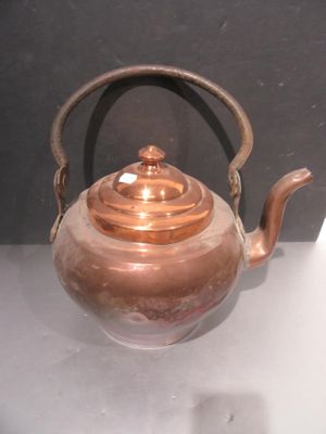 a copper tea pot with a handle on a table