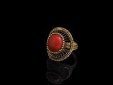 une bague en or sertie d'une pierre rouge sur un fond noir