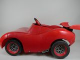 a red toy car that is sitting on a white surface