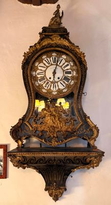 une horloge accrochée au mur à côté d'un tableau représentant un oiseau
