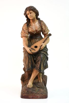 statue d'une femme assise sur un rocher, une guitare à la main