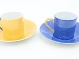 two cups and saucers that are sitting on a table