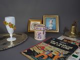 une table sur laquelle se trouvent un vase, un livre et des photos