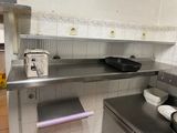 une cuisine équipée de plans de travail en inox et d'un lave-vaisselle