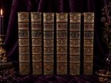 five old books on a table with a candle on it