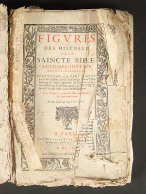 an old book is open on a table with a black background