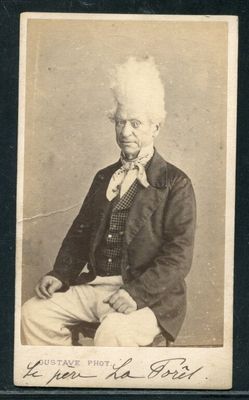 une vieille photo représentant un homme en costume-cravate, assis sur une chaise