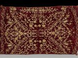 un gros plan sur un tissu brodé de rouge et d'or, orné de motifs floraux