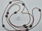 un gros plan d'un long collier composé de perles noires sur un fond blanc