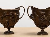 deux vases en bronze posés sur une table, sur fond blanc