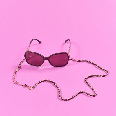 une paire de lunettes de soleil attachée à une chaîne sur fond rose