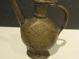 an antique brass teapot on a white table with a black background