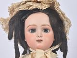 a close up of a doll wearing a dress and a hat