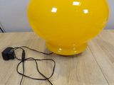 a yellow vase sitting on a wooden table next to a charger