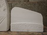 two white stone sculptures on a table next to a brick wall