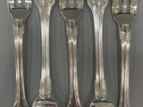 six forks and a knife are arranged in a row on a table