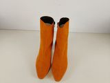 une paire de bottes orange posée sur une table blanche