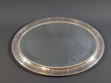 an oval silver tray with a beaded edge on a table